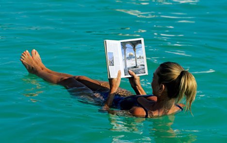 Nằm trên mặt nước tha hồ thư giãn và đọc báo Dead-sea